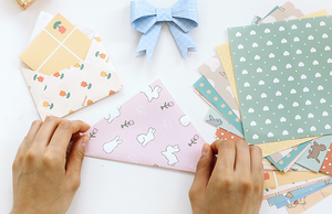 An assortment of adorable origami paper being folded by a pair of hands